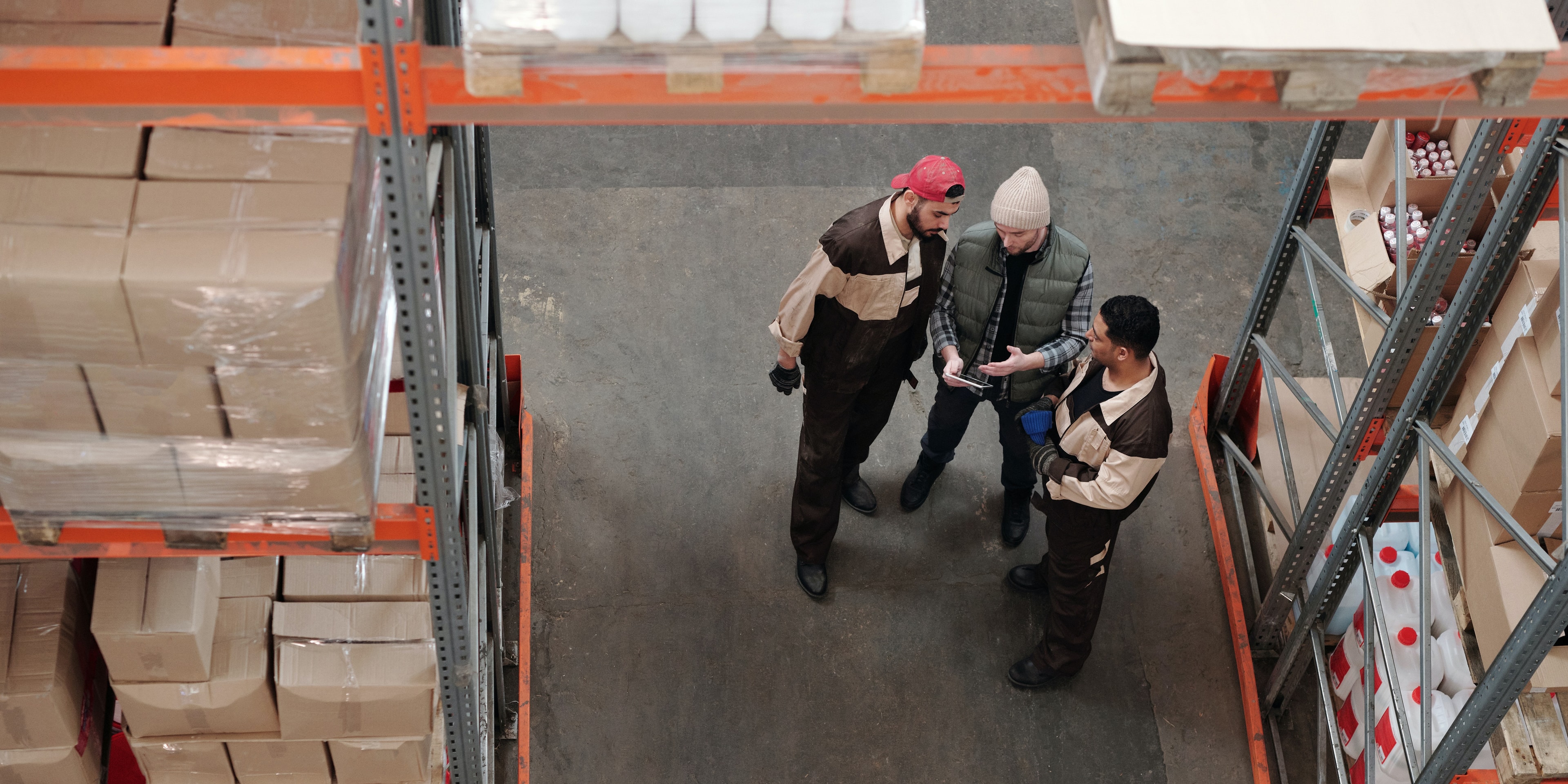 multi-warehouse-touchtribe Drie mannen die in een warehouse werken, staan gebogen over een tablet samen.
